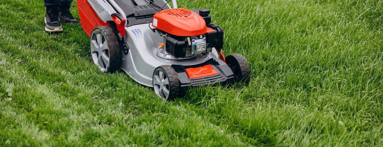 Man cutting grass with lawn mover in the back yard